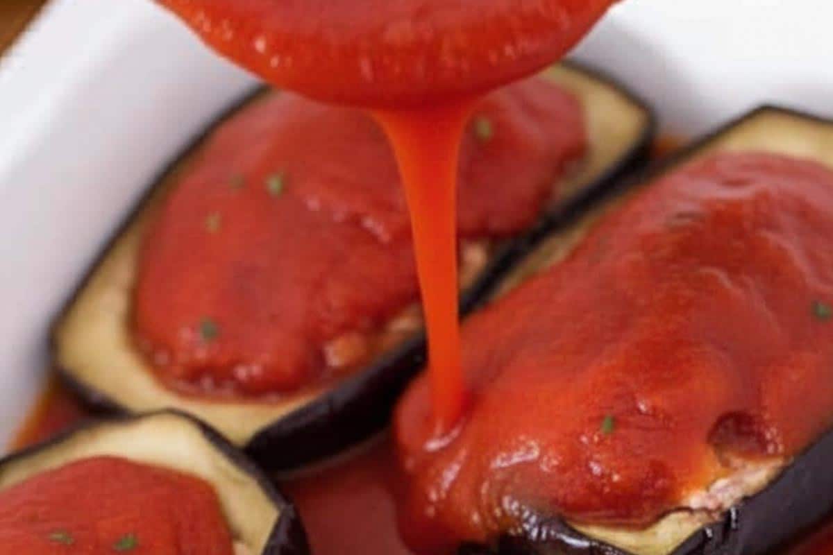Pouring the remaining tomato sauce over the tops.