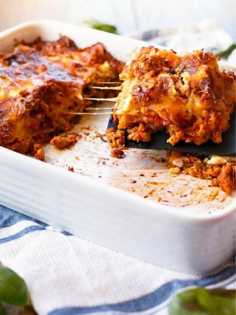 a side view of Chicken Pumpkin Ricotta Lasagna with half of the lasagna taken out and a large slice on a plastic spoon being taken out. - 11