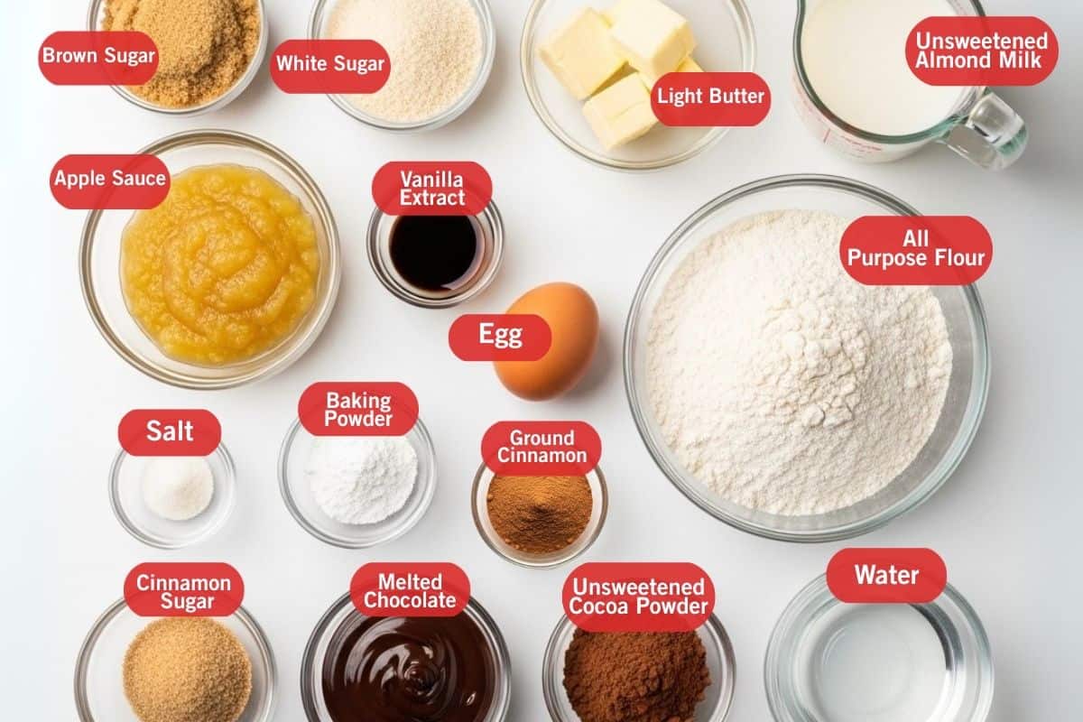 Flay lay photo of ingredient shot of  brown sugar, white sugar, light butter, unsweetened almond milk, all purpose flour, water, unsweetened cocoa powder, melted chocolate, cinnamon sugar, salt, baking powder, egg, ground cinnamon, vanilla extract and apple sauce