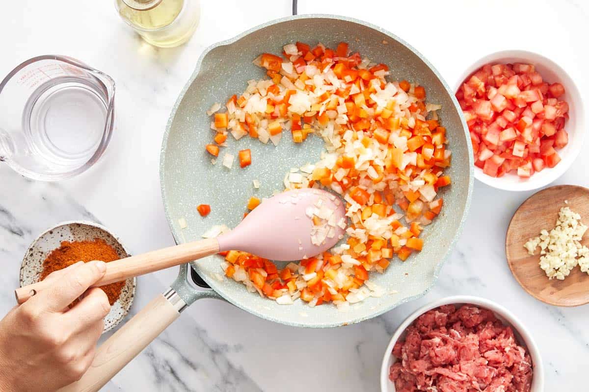 Frying onion and red capsicum in a skillet.