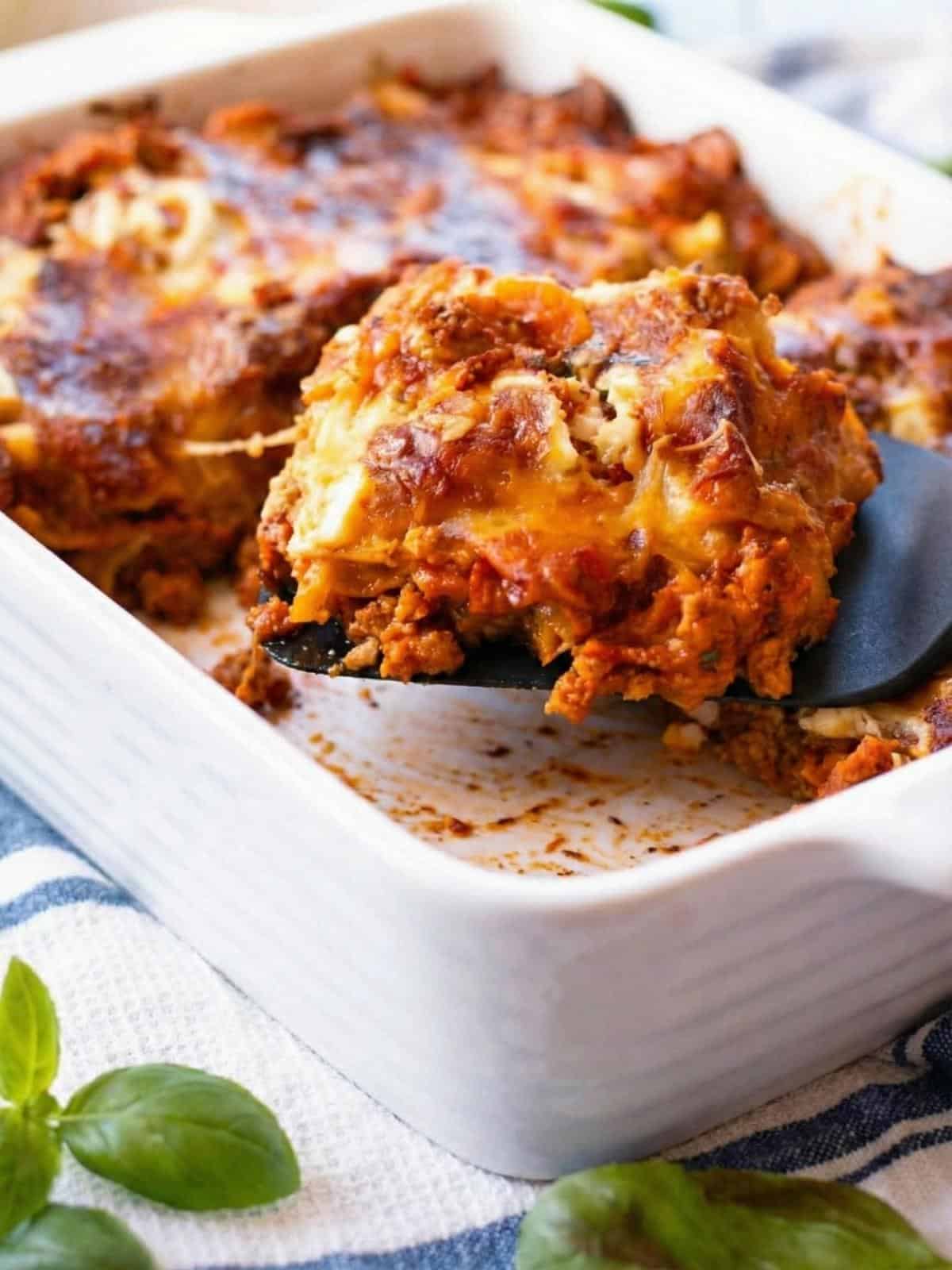 pumpkin and ricotta lasagna in a white baking dish with a slice coming out. - 1