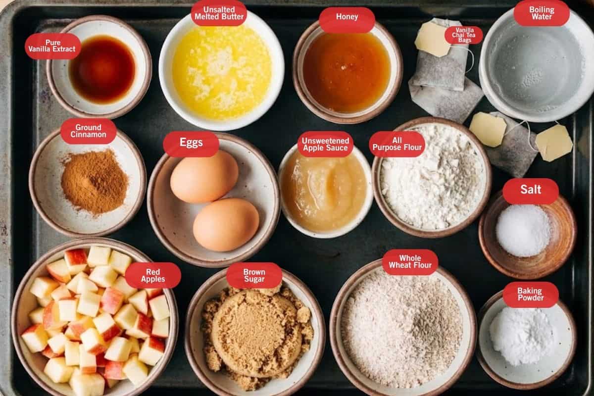 Flat lay photo of ingredient shot of vanilla chai tea bags, boiling water, medium red apples, ground cinnamon, pure vanilla extract, brown sugar, eggs, unsalted melted butter, unsweetened apple sauce, honey, whole wheat flour, all purpose flour. baking powder, salt - 2