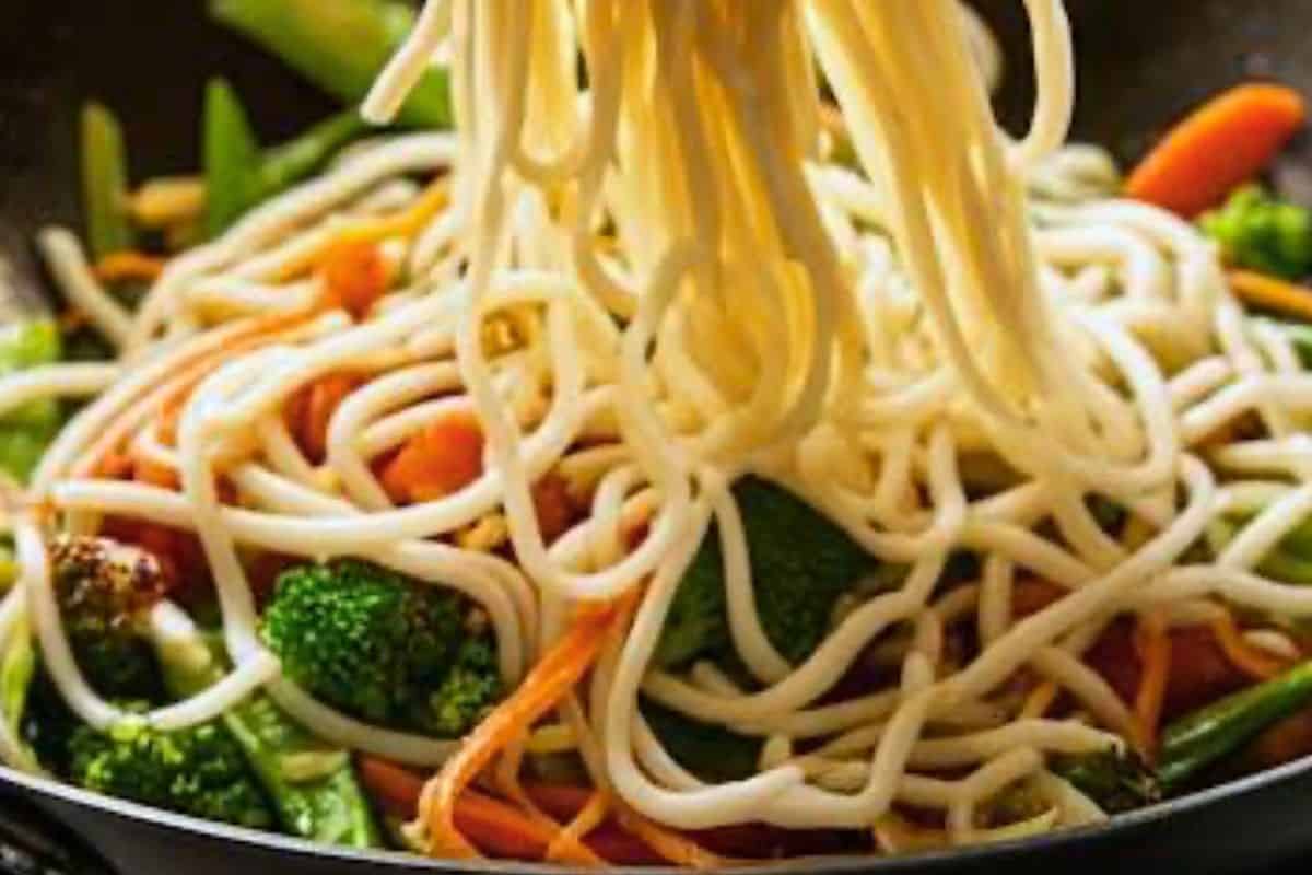 add the udon noodles to the wok and gently toss with the sauce and vegetables