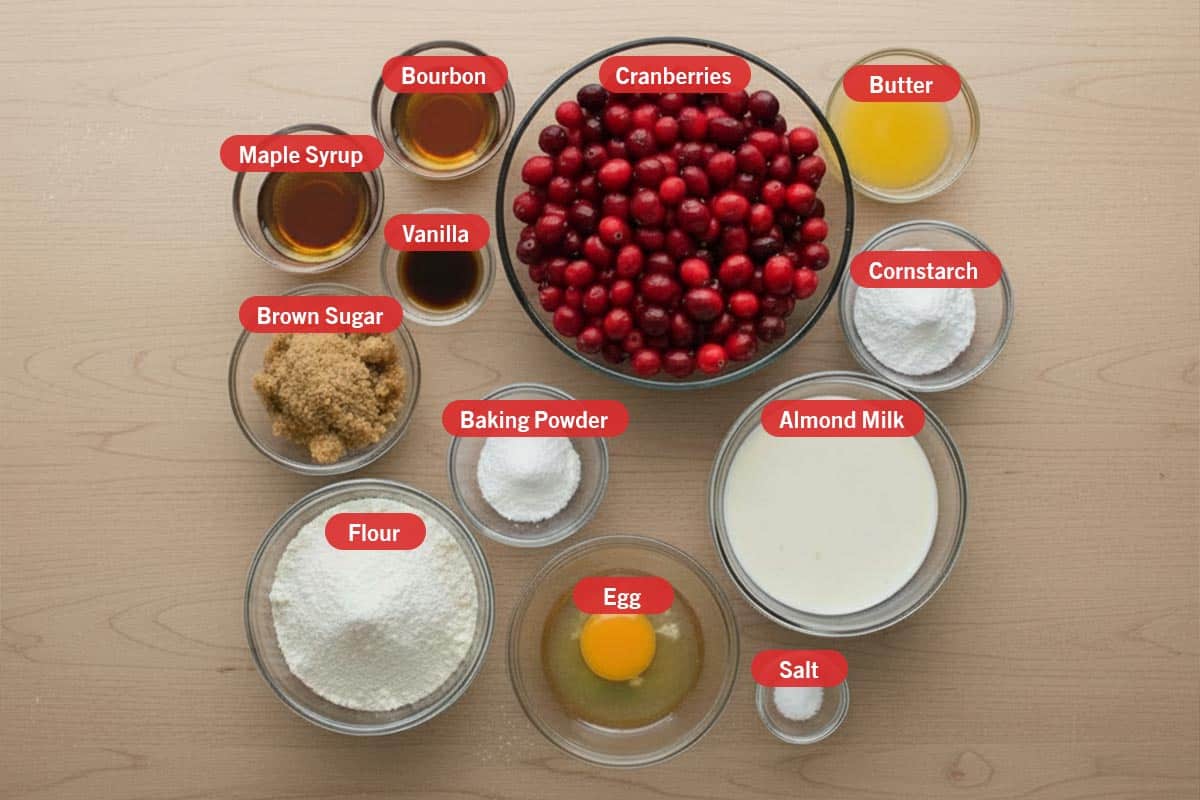 Top shot of ingredients: maple syrup,  bourbon, vanilla, cranberries, butter, cornstarch, brown sugar, baking powder, flour, egg, salt, and almond milk. - 2