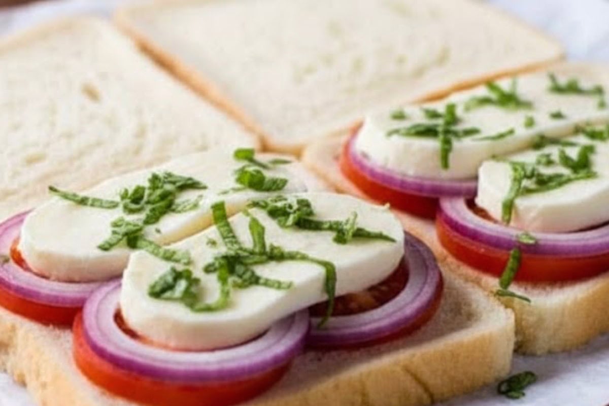 Top two slices with mozzarella, tomato, sliced onion, and chopped basil.