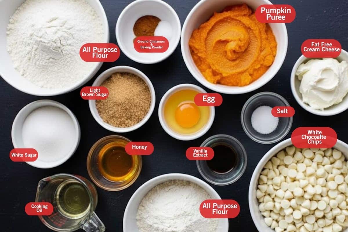 Flat lay photo of ingredient shot of all purpose flour, ground cinnamon and baking powder, pumpkin puree, fat free cream cheese, salt, white chocolate chips, vanilla extract, egg, honey, cooking oil, white sugar, light brown sugar
