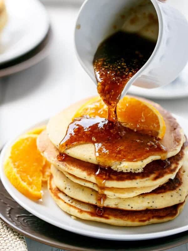 Orange Poppyseed dressing being dripped over Pancakes