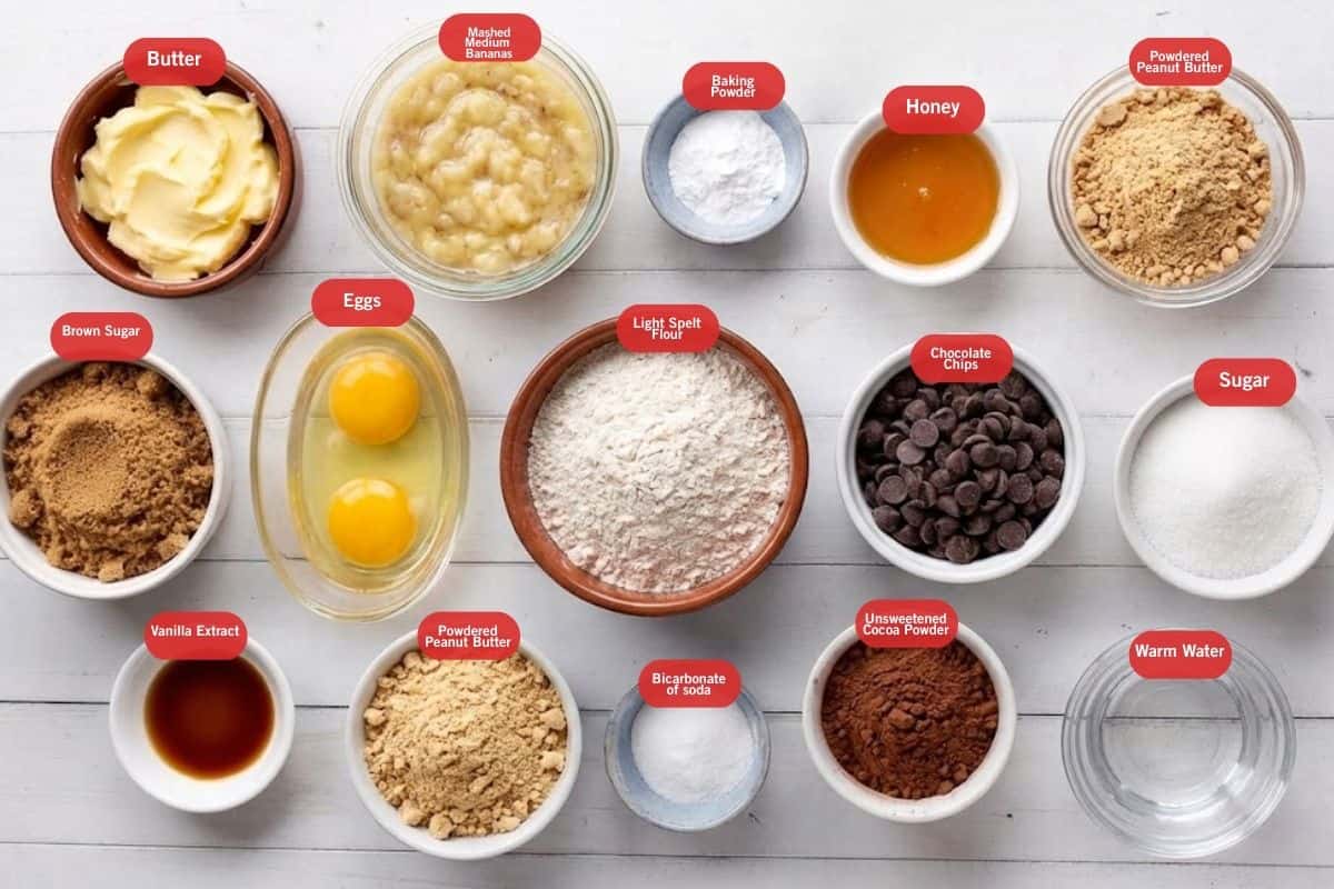 Flat lay photo of ingredient sot of butter, mashed medium butter, baking powder, honey, powdered peanut butter, sugar, warm water, unsweetened cocoa powder, chocolate chops, light spelt flour, bicarbonate of soda, eggs, baking powder, butter, brown sugar, vanilla extract - 2