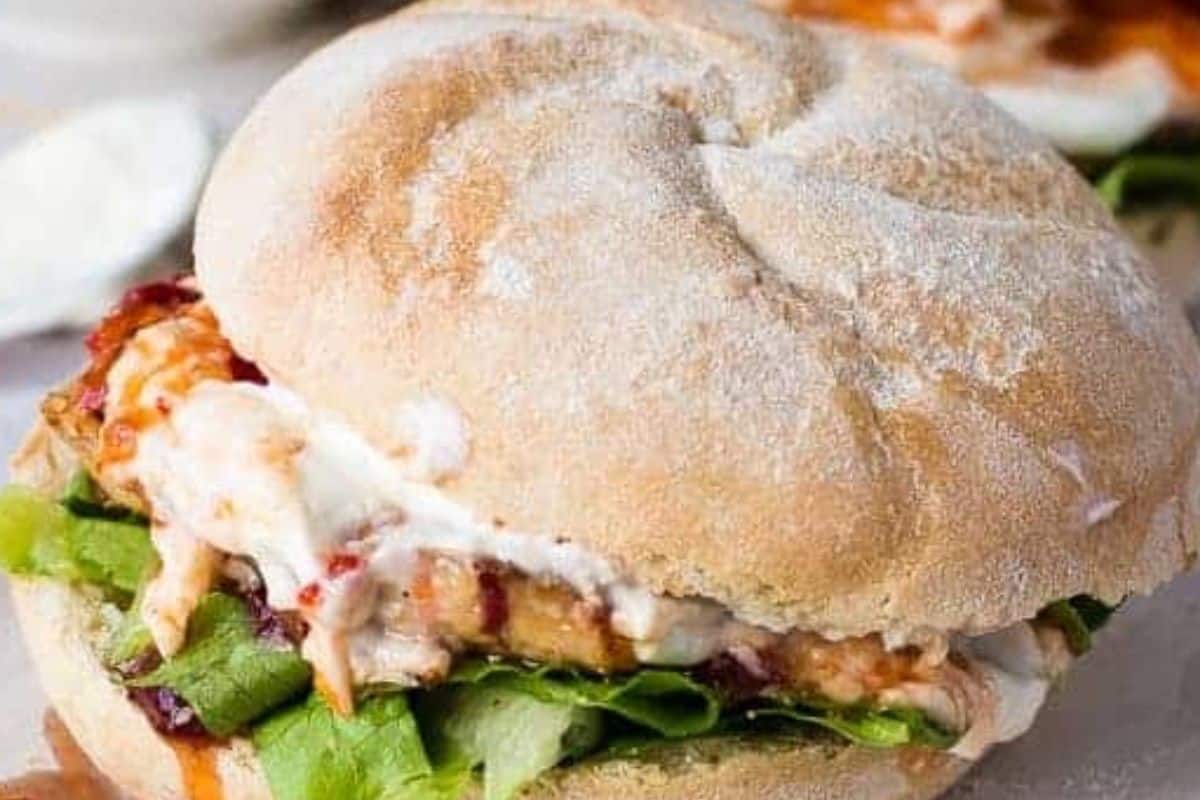 Slice and divide buns between plates. Layer lettuce, a patty, and a spoonful of sour cream. Drizzle with sweet chili sauce.