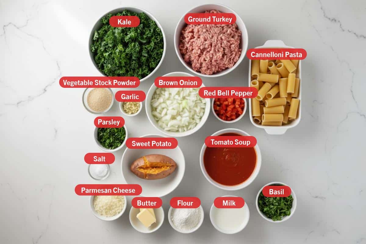 Top shot of ingredients: kale, ground turkey, cannelloni pasta, vegetable stock powder, garlic, brown onion, red bell pepper, parsley, salt, sweet potato, tomato soup, parmesan cheese, butter, flour, milk, and basil. - 2
