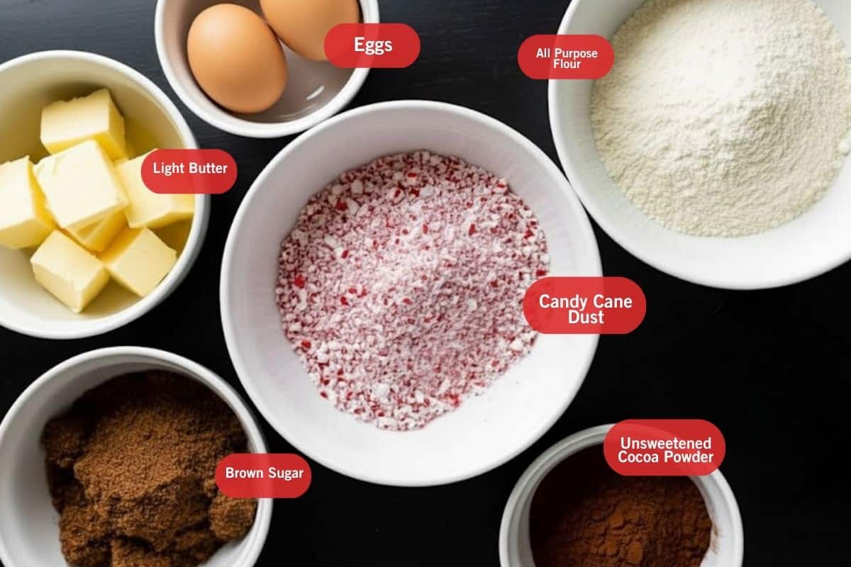 Flat lay photo of ingredient shot of light butter, eggs, all purpose flour, candy cane dust, brown sugar and unsweetened cocoa powder