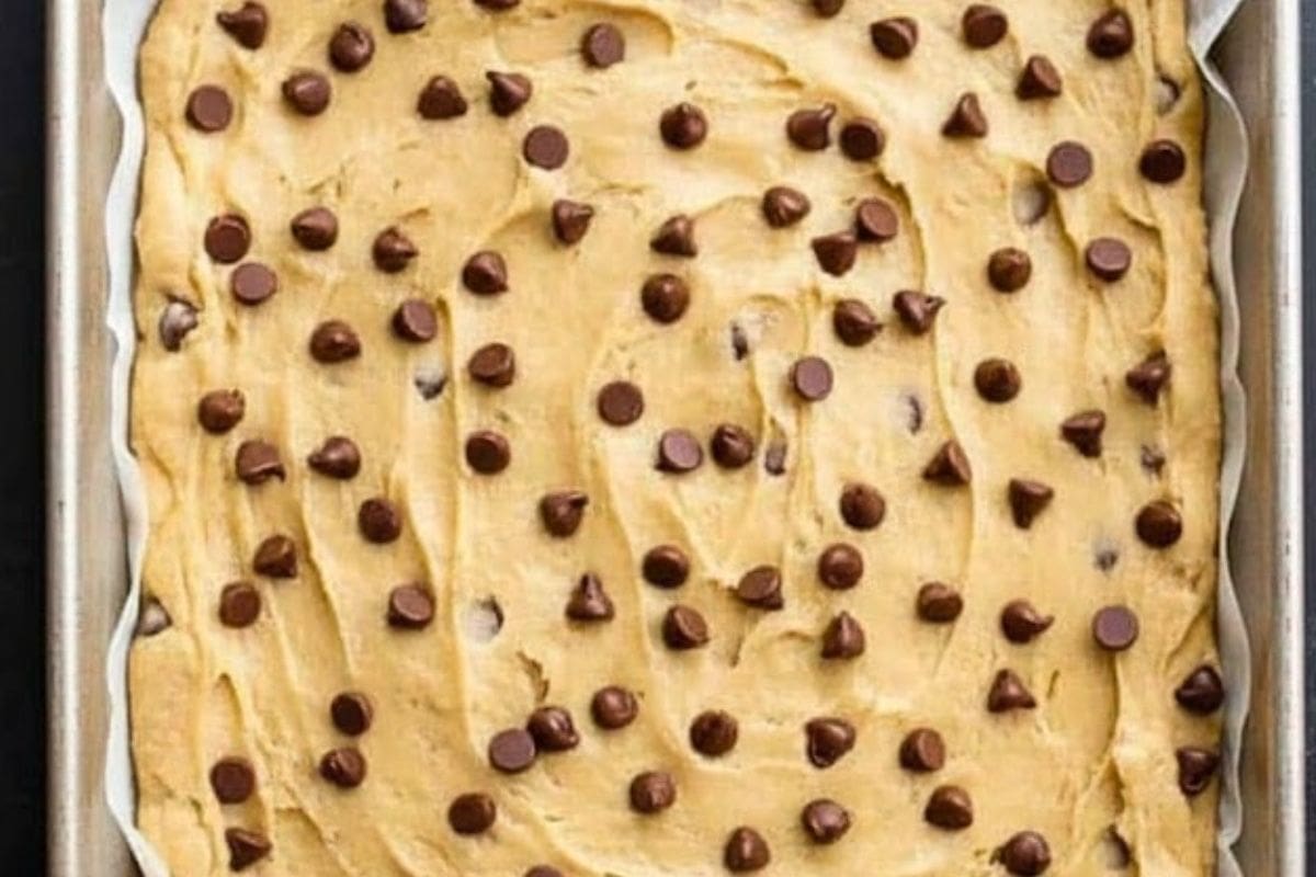 Spread the dough evenly onto the prepared tray, leaving about an inch from the edges. Sprinkle chocolate chips on top.