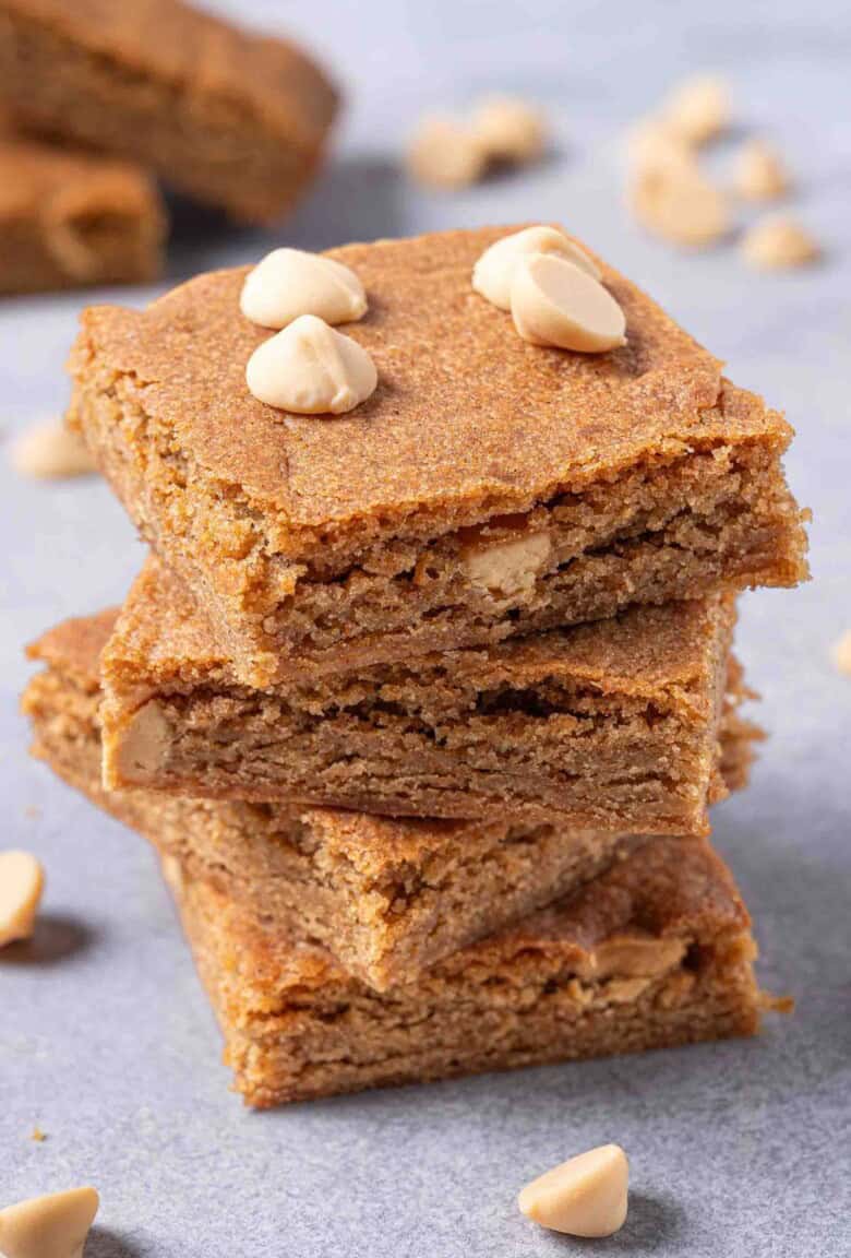 Three beautiful blondies stacked together with white caramel on top.