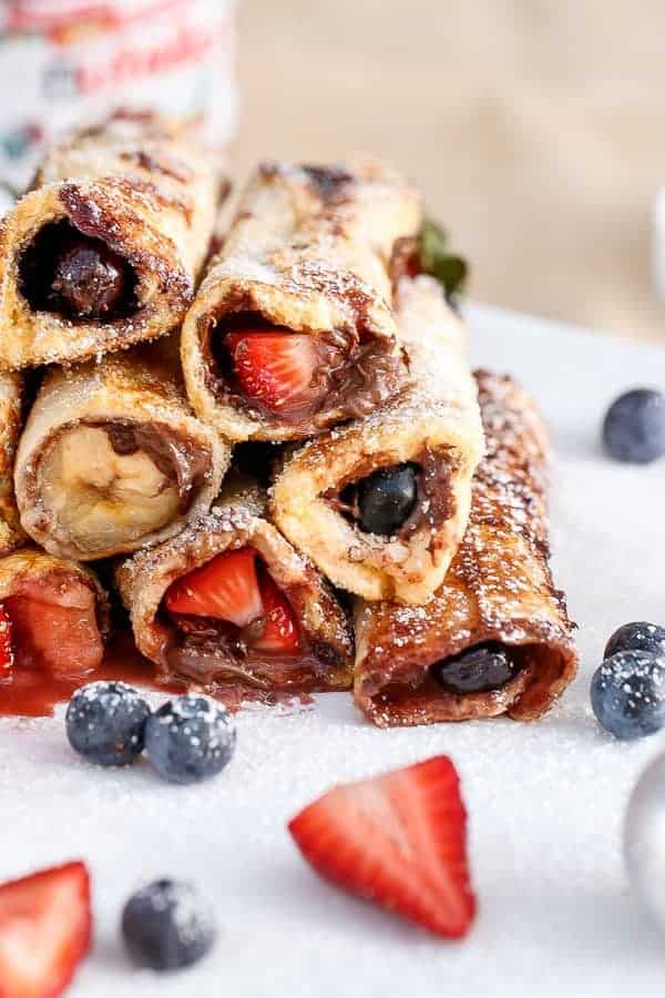 Side view of Nutella Fruit French Toast Cannoli on a plate with some fresh berries kept aside  