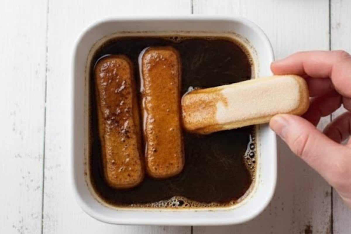 Pour the cooled coffee into a shallow bowl and dip each sponge finger half on both sides until coated. - 5