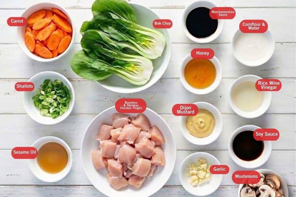 Flat lay photo of ingredient shot of carrot, wok chop, Worcestershire sauce, cornflour and water, rice wine vinegar, soy sauce, mushrooms garlic, dijon mustard, honey, boneless and skinless chicken thighs, sesame oil, shallots