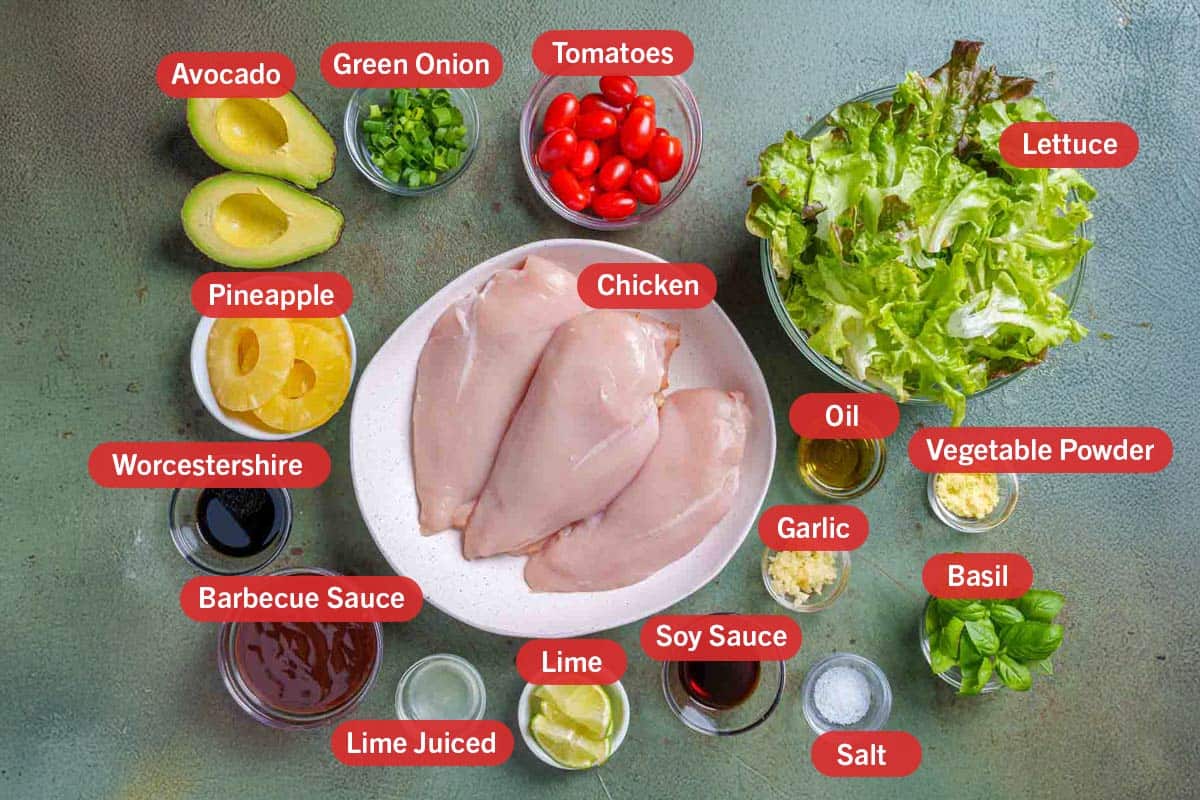Image of all the needed ingredients for the preparation of this recipe, specifically: chicken, lettuce, oil, vegetable powder, garlic, basil, soy sauce, salt, lime, lime juice, barbecue sauce, worcestershire sauce, pineapple, avocado, green onion, tomatoes.
