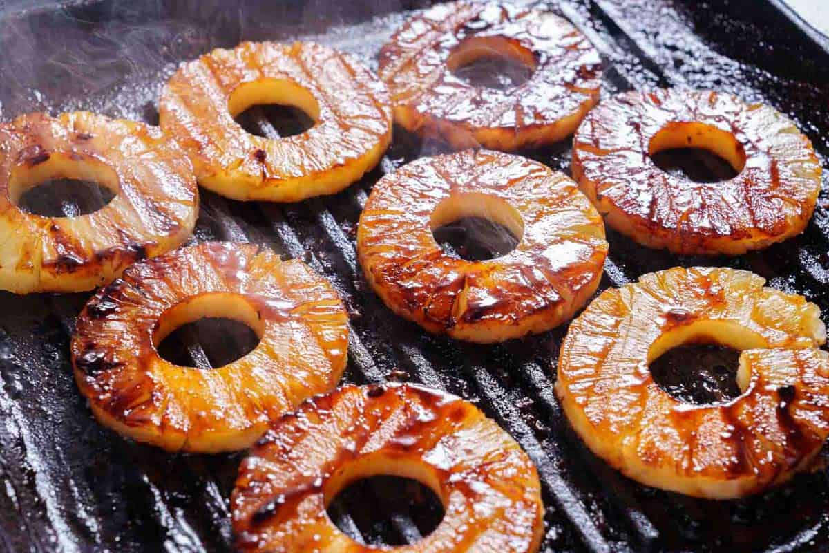 pineapple slices being grilled into the same pan where chicken was being cooked