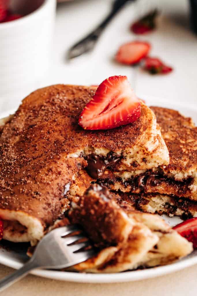 A slice of strawberry on a Chocolate Stuffed Churro Pancakes.