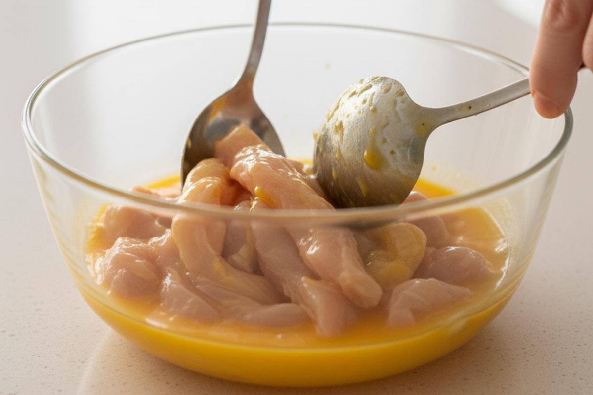 Coating the chicken strips in the bowl with the egg mixture. - 5