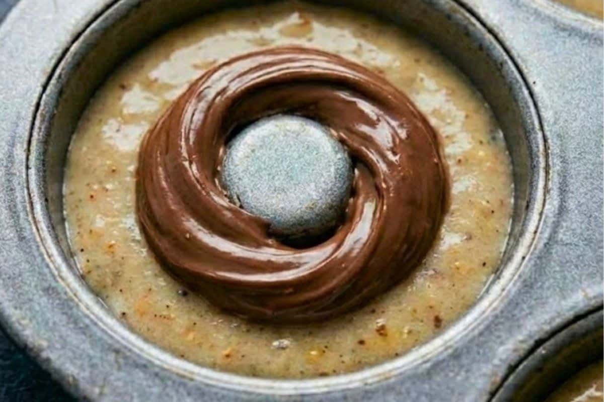 Spoon batter into the pans until halfway full. Spoon 1 teaspoon of Nutella over the batter, then carefully cover with more batter to seal - 6