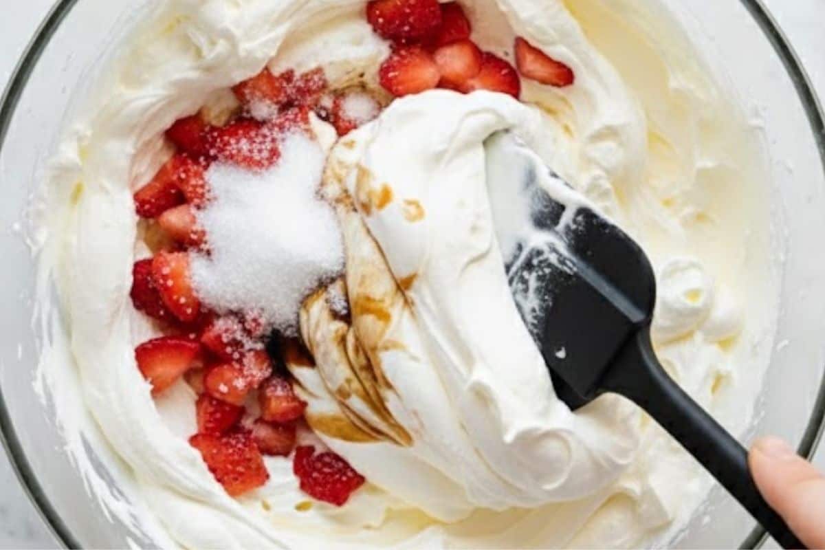 Whip the cream with the extra sugar and vanilla, chop half of the macerated strawberries, and fold them gently into the cream.