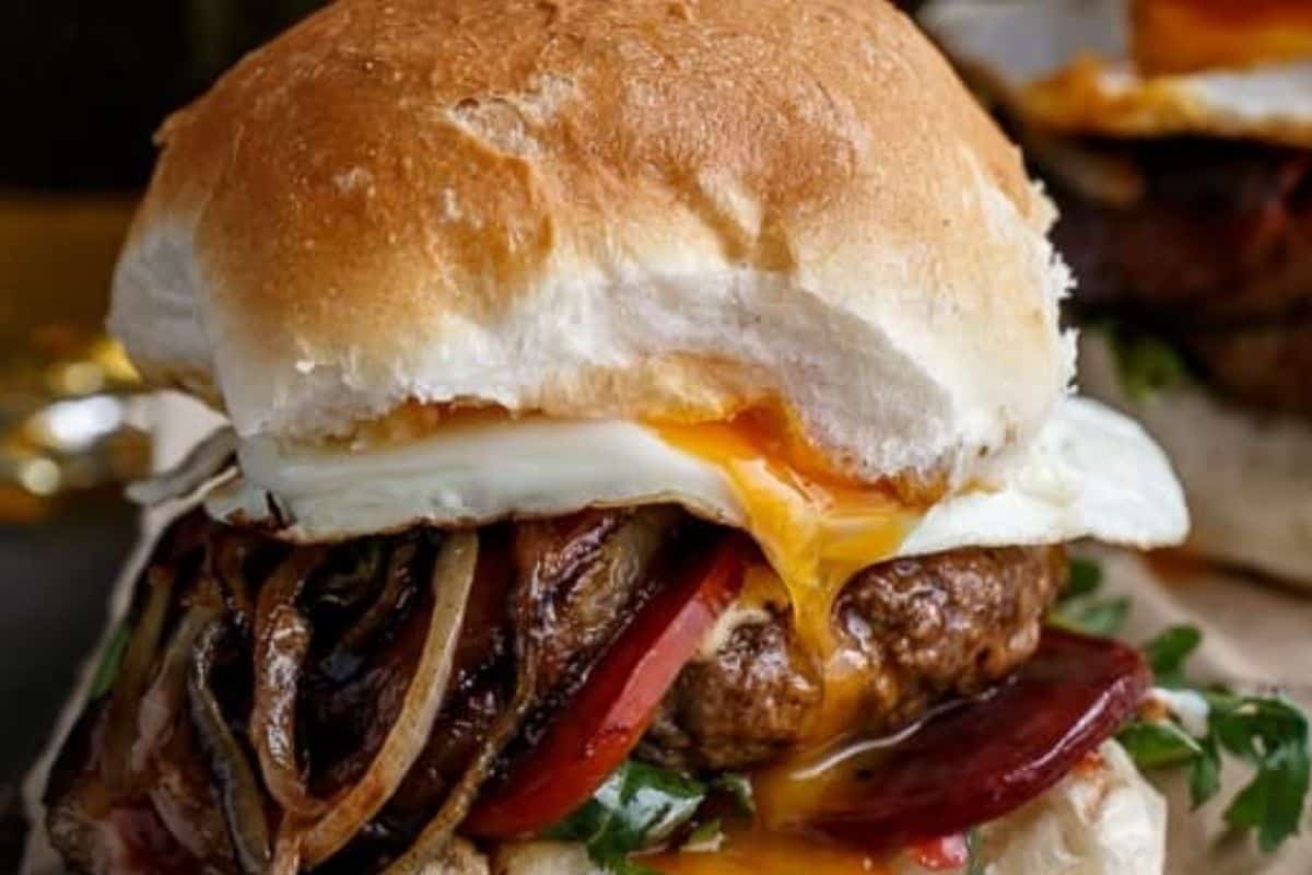 Layer buns with lettuce, beetroot, a patty, cheese, pineapple, bacon, onion, tomato, and a fried egg. Drizzle with tomato sauce and mayonnaise, then top with the remaining bun.