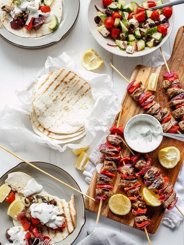 Greek Lamb Souvlaki with a Garlic Yogurt Dip on a wooden platter with some tortilla