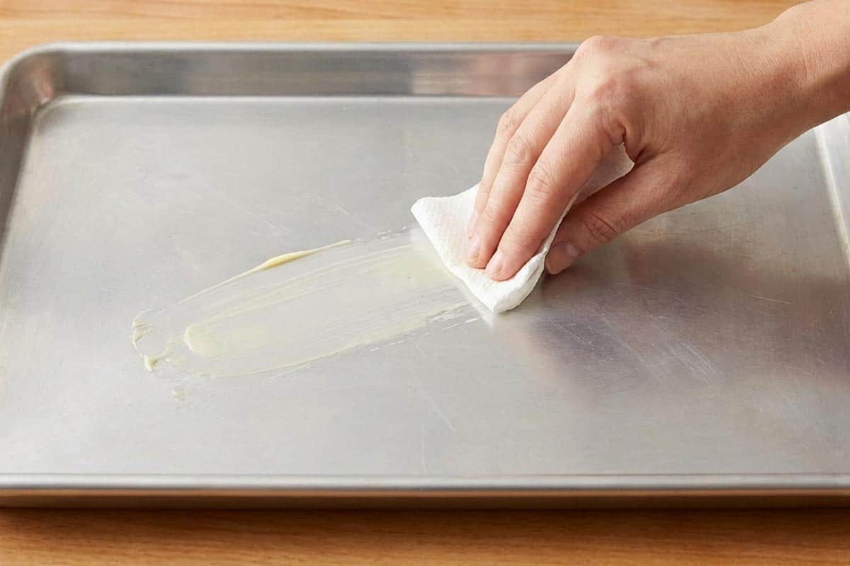 Lightly greasing a baking tray. - 3