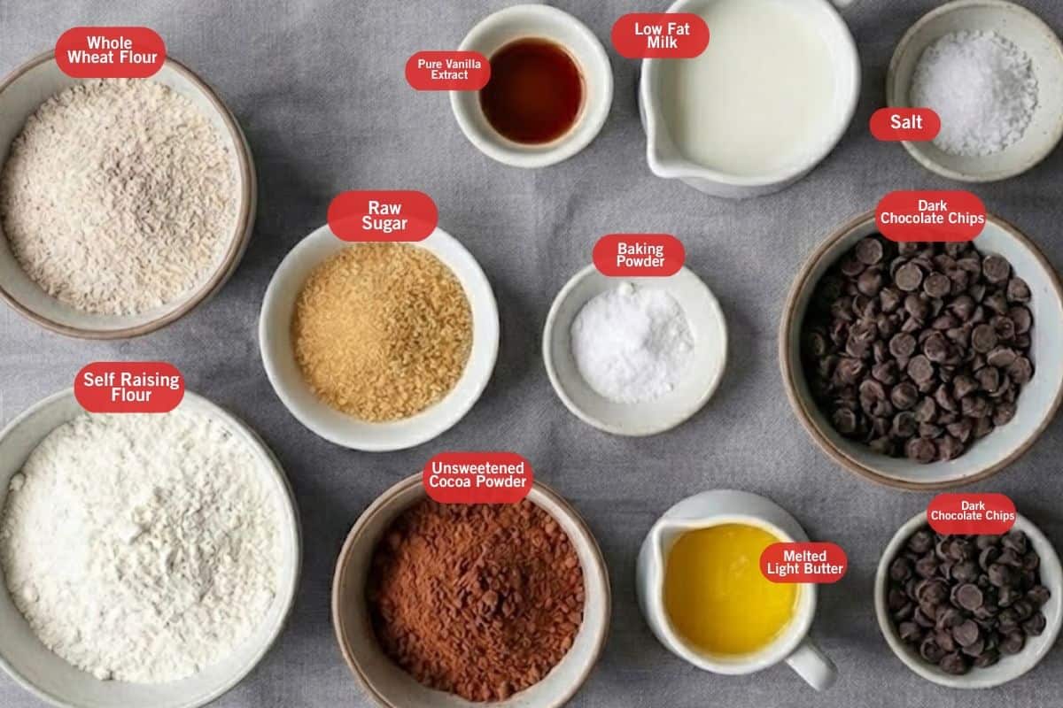 Flat lay photo of ingredient shot of whole wheat flour, self raising flour, raw sugar, pure vanilla extract, unsweetened cocoa powder, low fat milk, baking powder, salt, dark chocolate chip, melted light butter