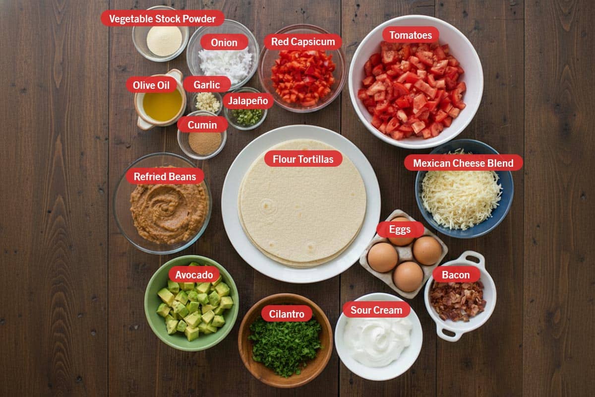 Top shot of ingredients: vegetable stock powder, onion, red capsicum, olive oil, garlic, jalapeño, cumin, tomatoes, flour tortillas, mexican cheese blend, eggs, bacon, sour cream, cilantro, avocado, and refried beans. - 2