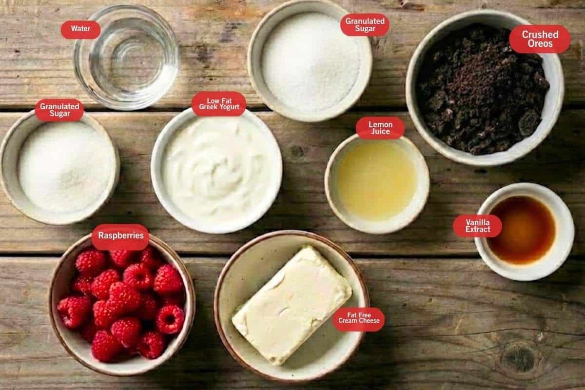 Flat lay photo of ingredient shot of water, granulated sugar, crushed oreos, vanilla extract, lemon juice, low fat greek yogurt, raspberries, fat free cream cheese - 2