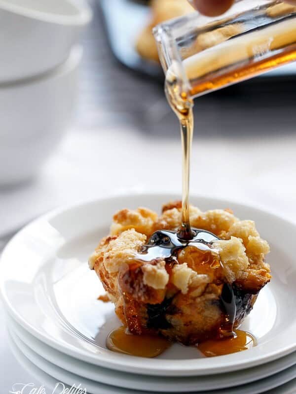 Maple syrup dripping over Blueberry Cheesecake French Toast Streusel Muffins