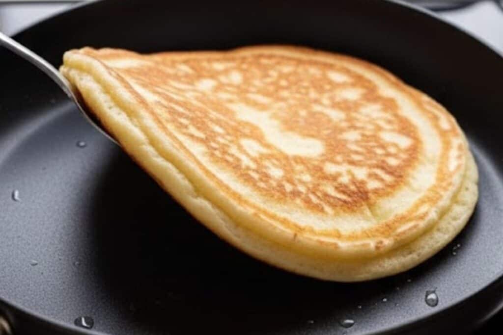 Once the underside turns golden, flip carefully with a spatula and cook until both sides are evenly golden and puffed.
