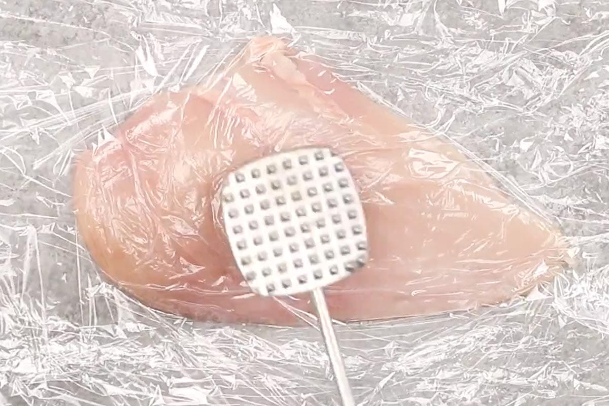Pounding the chicken between two sheets of plastic wrap. - 3