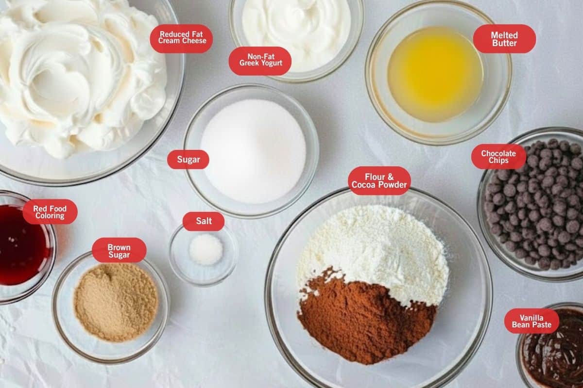 Flat lay photo of ingredient shot of reduced fat cream cheese, non-fat Greek yogurt, melted butter, chocolate chips, vanilla bean paste, flour and cocoa powder, red food coloring, salt, sugar, brown sugar