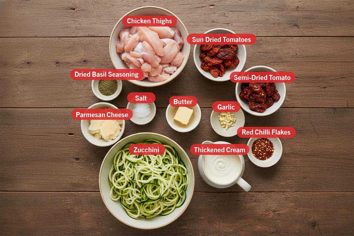 Top shot of ingredients: chicken thighs, sun dried tomatoes, semi-dried tomatoes, dried basil seasoning, parmesan cheese, salt, butter, garlic, zucchini, thickened cream, and red chilli flakes.