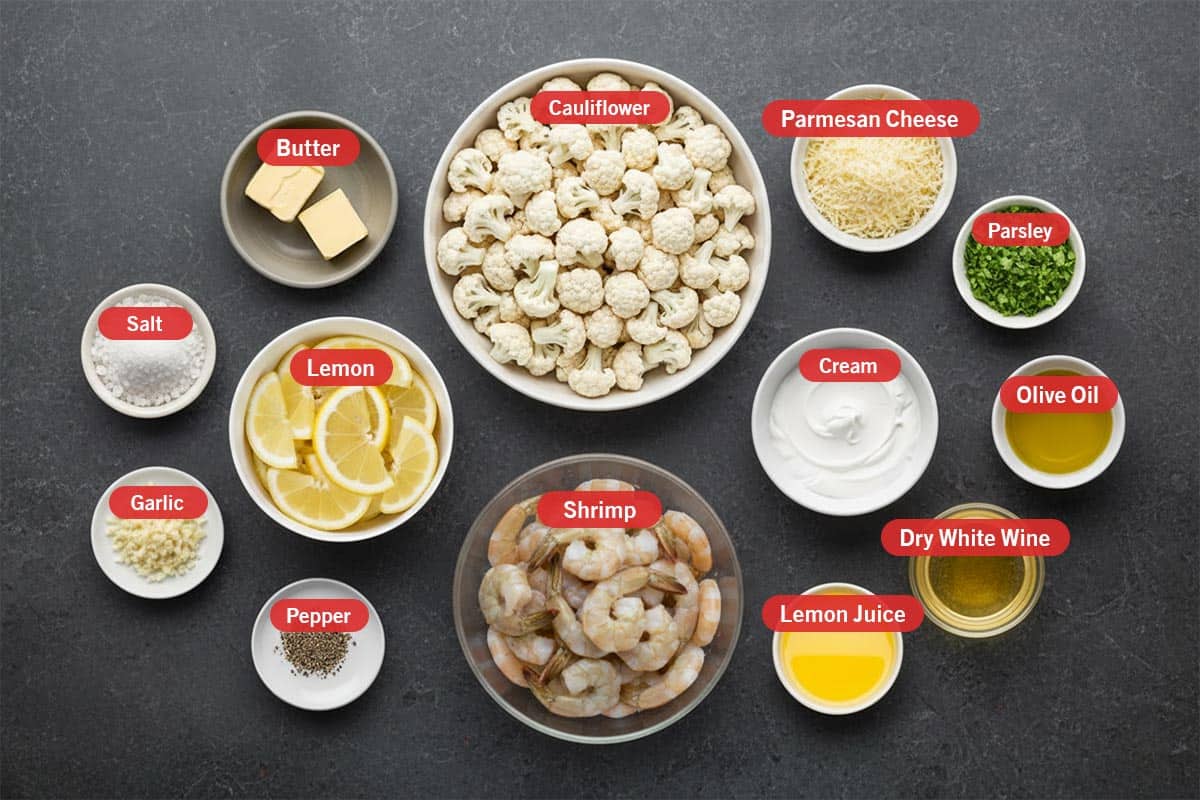 Top shot of ingredients: cauliflower, parmesan cheese, parsley, olive oil, cream, dry white wine, lemon juice, shrimp, butter, salt, lemon, garlic, and pepper.