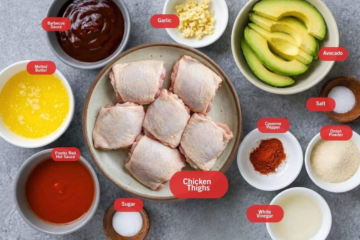 Flat lay photo of barbecue sauce, garlic, avocado, salt, onion powder, cayenne pepper, white sugar, chicken thighs, sugar, frank red hot sauce, melted butter