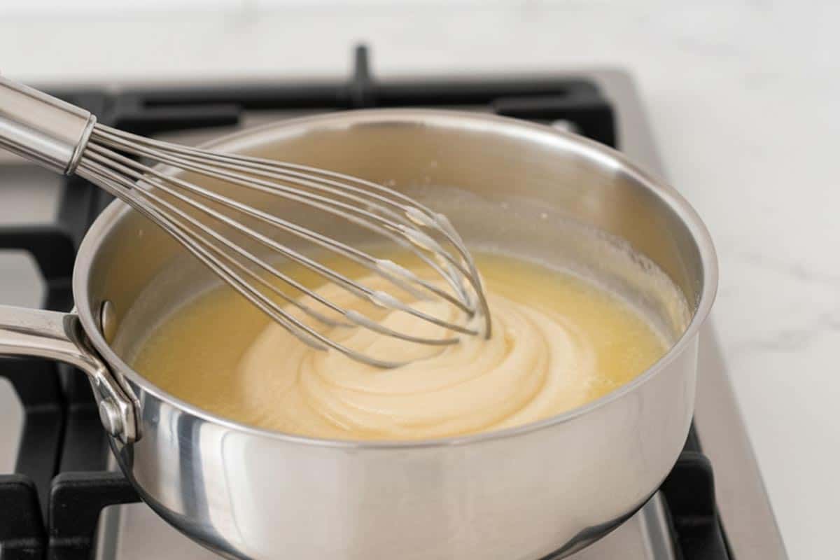 Whisking the flour with the melted butter in a smaller saucepan.