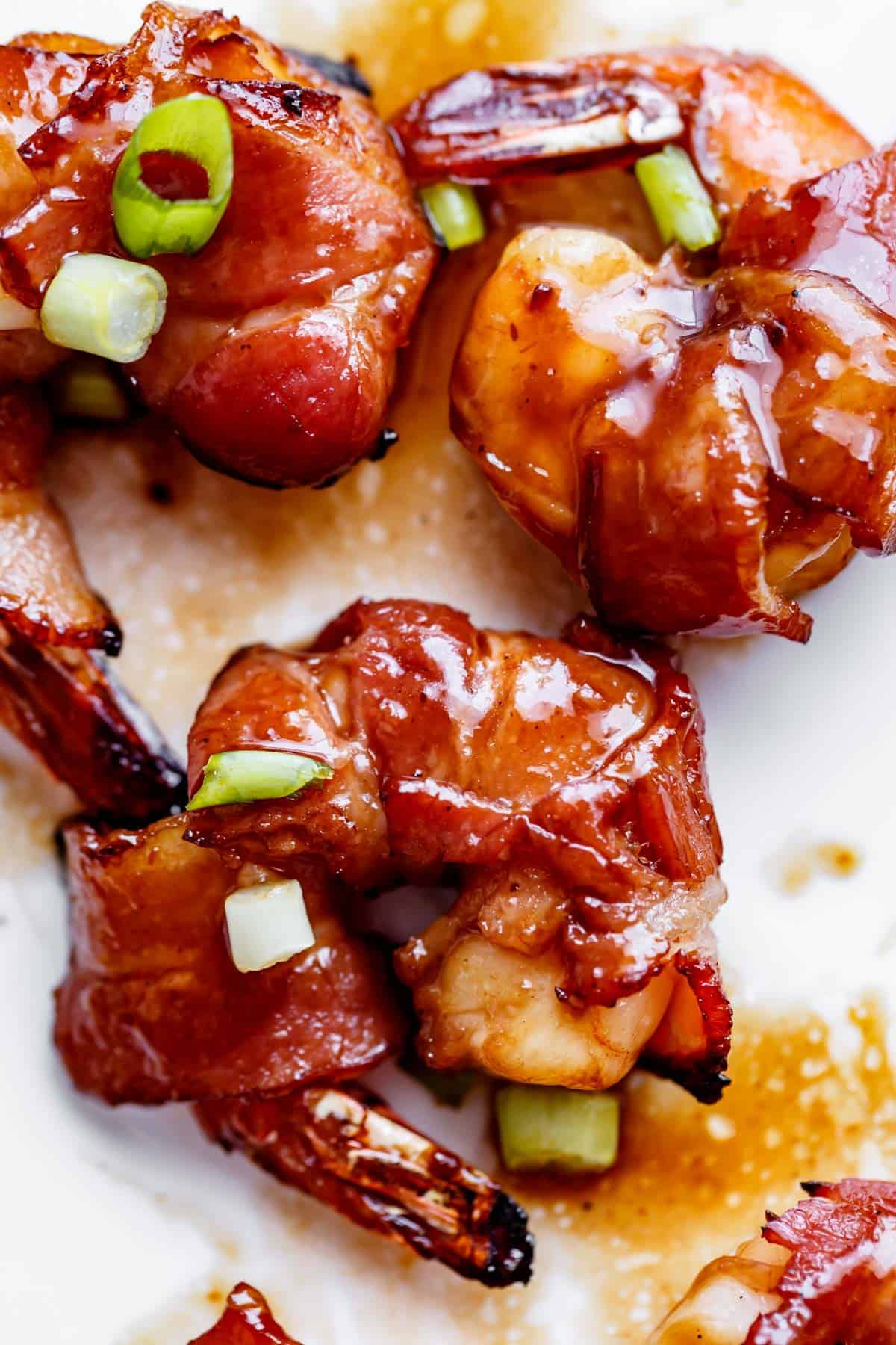 Close up of crispy, wrapped glazed prawns with chopped spring onions sprinkled on top. 