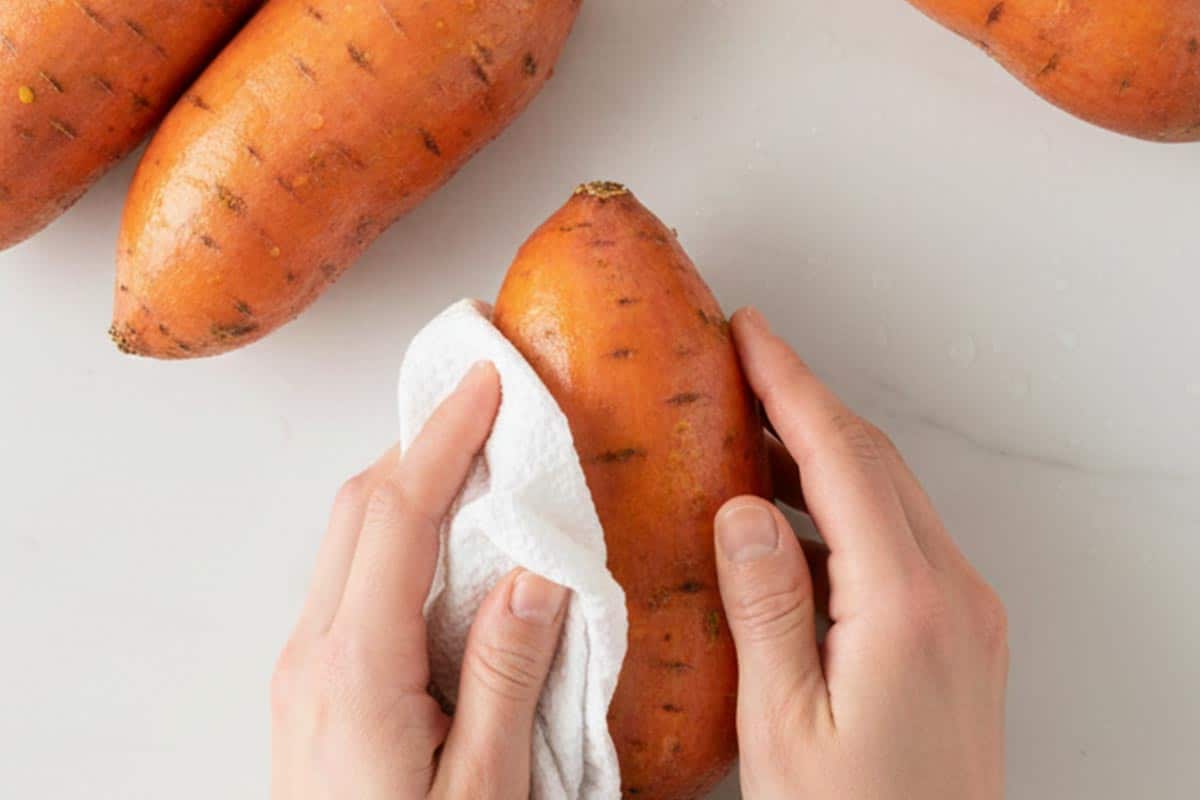 Patting the sweet potatoes dry with paper towel.