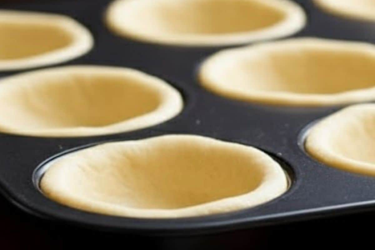 Lightly spray a 12 cup muffin pan with oil and gently press each dough round into the cups