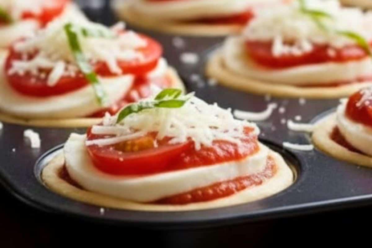 Start with two slices of mozzarella to protect the dough, then add one teaspoon of sauce, tomato slices, basil, mozzarella, and extra basil.