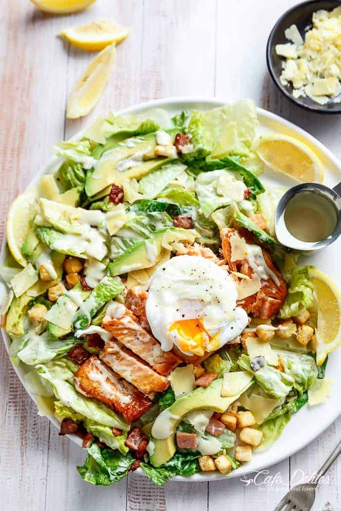 Crispy pan fried Salmon meets Caesar salad for a twist on the traditional! Easy to make with creamy avocado slices, crunchy croutons, the tang of shaved parmesan cheese, a perfect runny poached egg on top and a lightened up Caesar dressing!| http://cafedleites.com