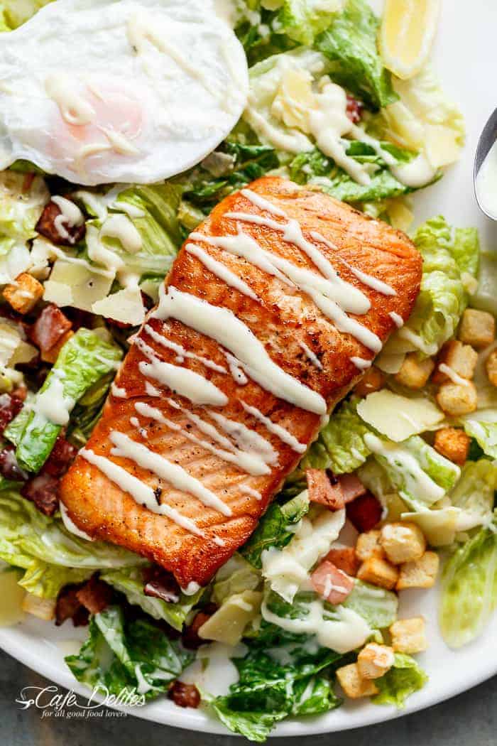 Crispy pan fried Salmon meets Caesar salad for a twist on the traditional! Easy to make with creamy avocado slices, crunchy croutons, the tang of shaved parmesan cheese, a perfect runny poached egg on top and a lightened up Caesar dressing!| http://cafedleites.com