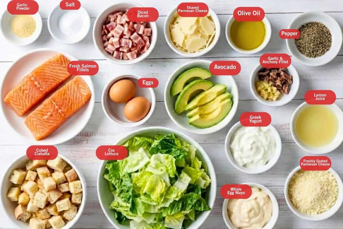 Flat lay photo of garlic powder, salt, diced bacon, shaved parmesan cheese, olive oil, pepper, fresh salmon fillets, avocado, garlic and anchovy fillet, lemon juice, eggs, cubed ciabatta, cos lettuce, greek yogurt, whole egg mayo, freshly grated parmesan cheese, olive oil,  - 2