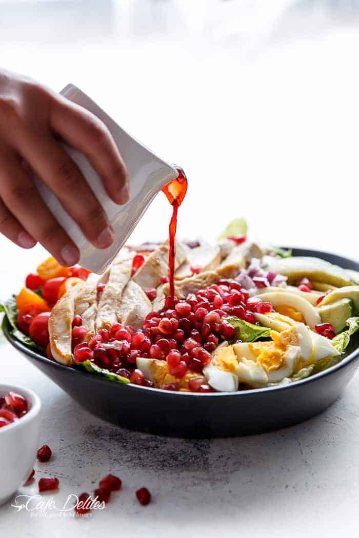  throwing fresh ingredients into a bowl with an abundance of Pomegranates Pomegranate Cobb Salad