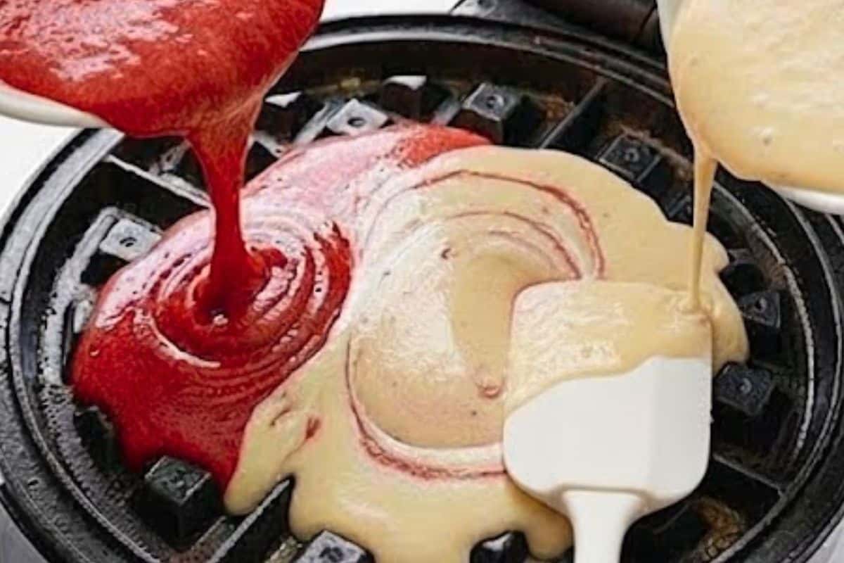  Lightly grease the waffle maker, then pour about 1/4 cup of red velvet batter, followed by 1/4 cup of vanilla batter. Swirl gently with a spatula to create a marbled effect - 9