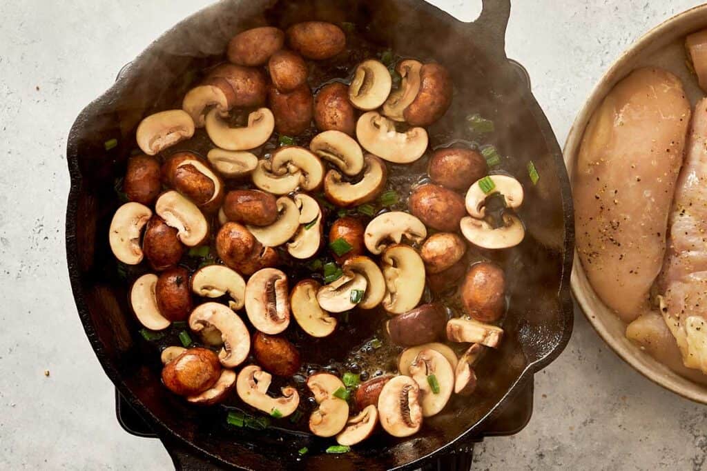 a skillet of mushrooms being browned off in a black skillet
